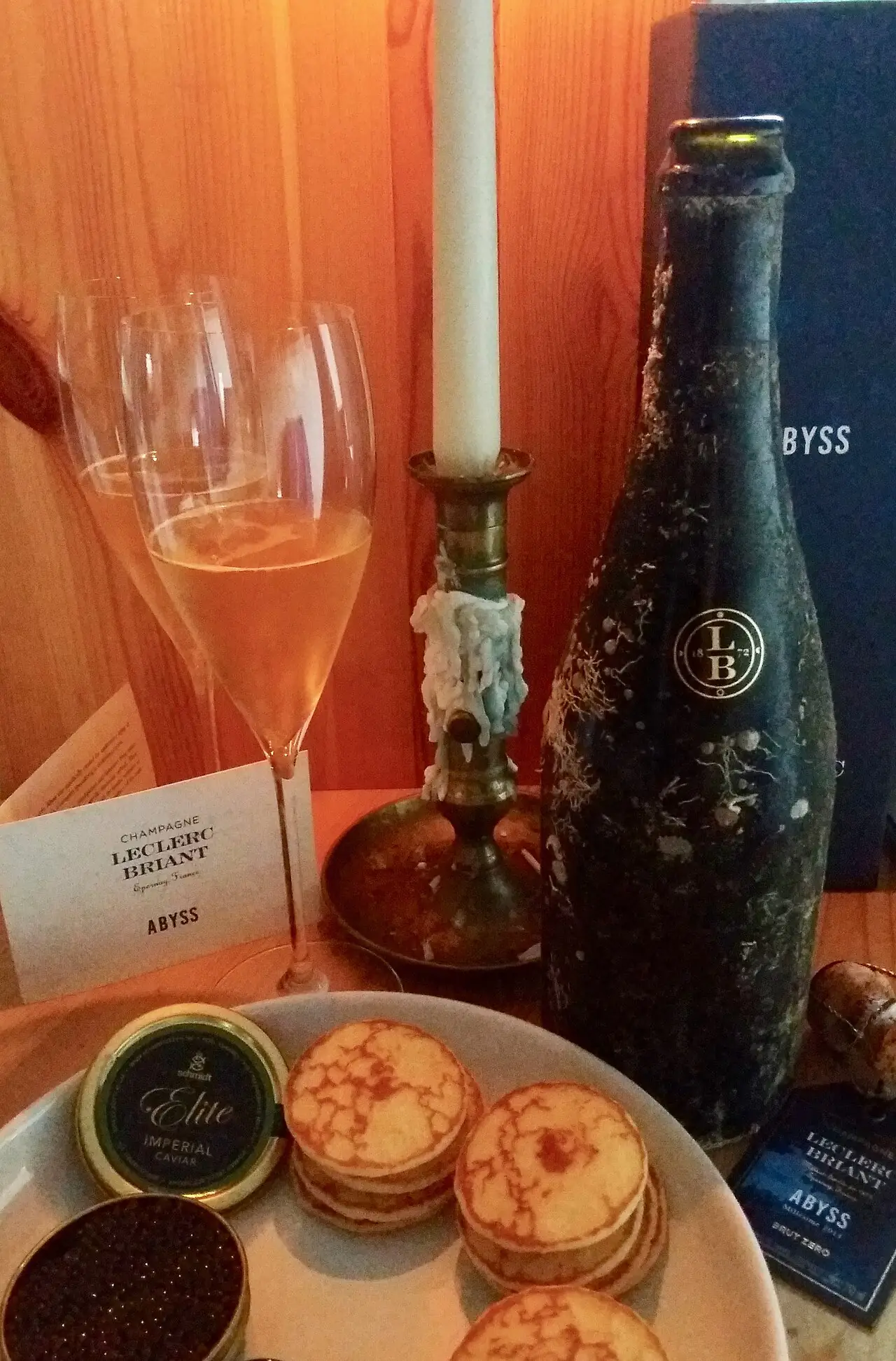 A bottle of Leclerc Briant Abyss Champagne beside glasses and its presentation box