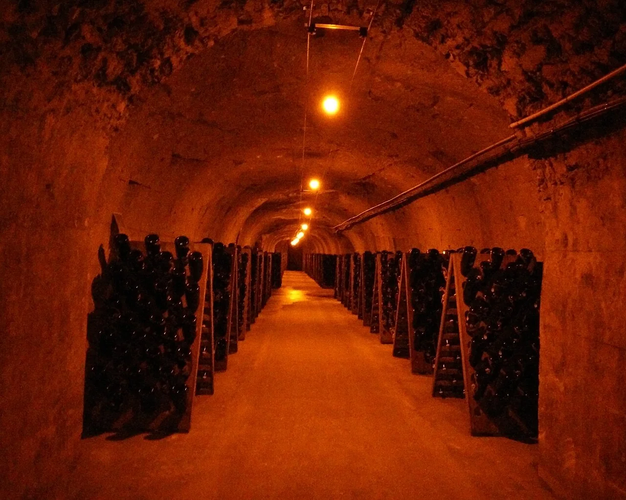 Rows of bottles in a vaulted Perrier-Jouët cellar in Épernay